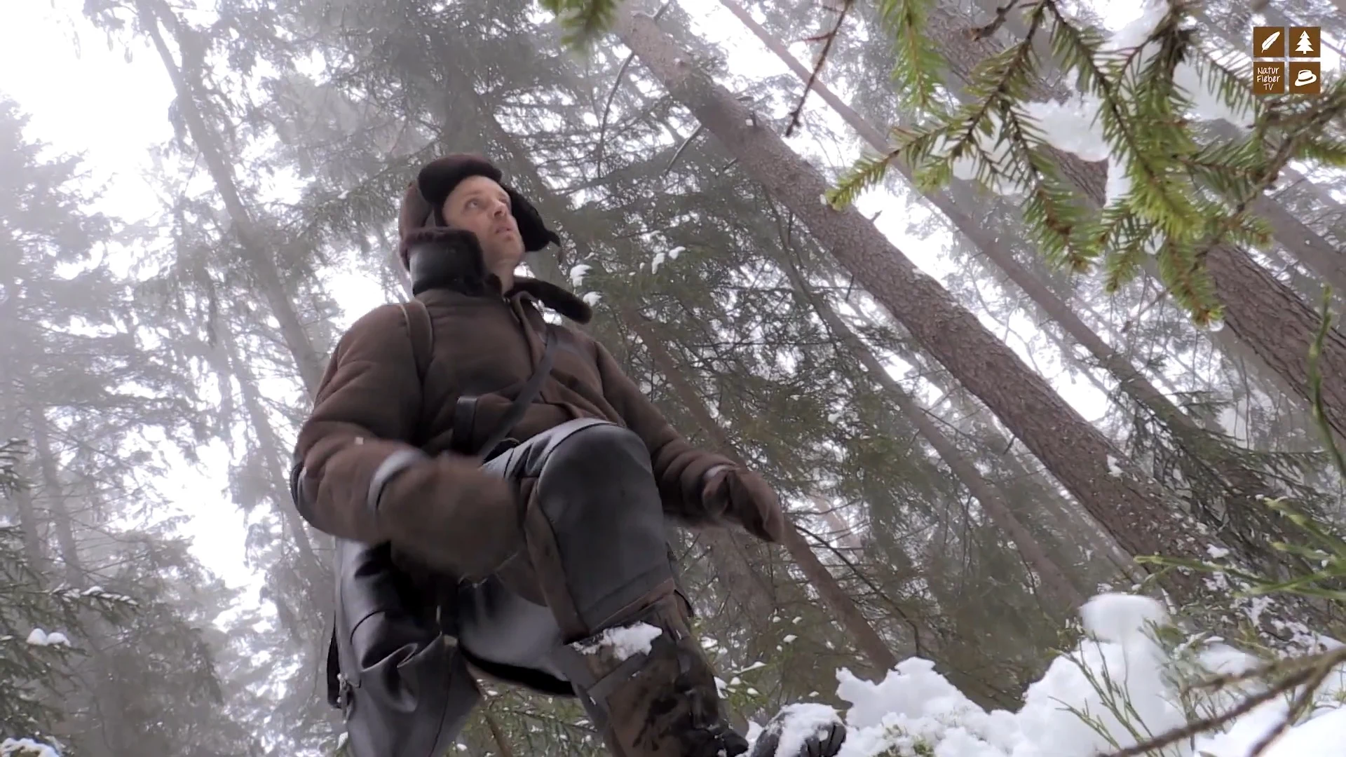Jäger in Lammfell-Stiefelhose und Jacke Hunter im verschneiten Bergwald, Standbild aus dem Video von Naturfieber TV