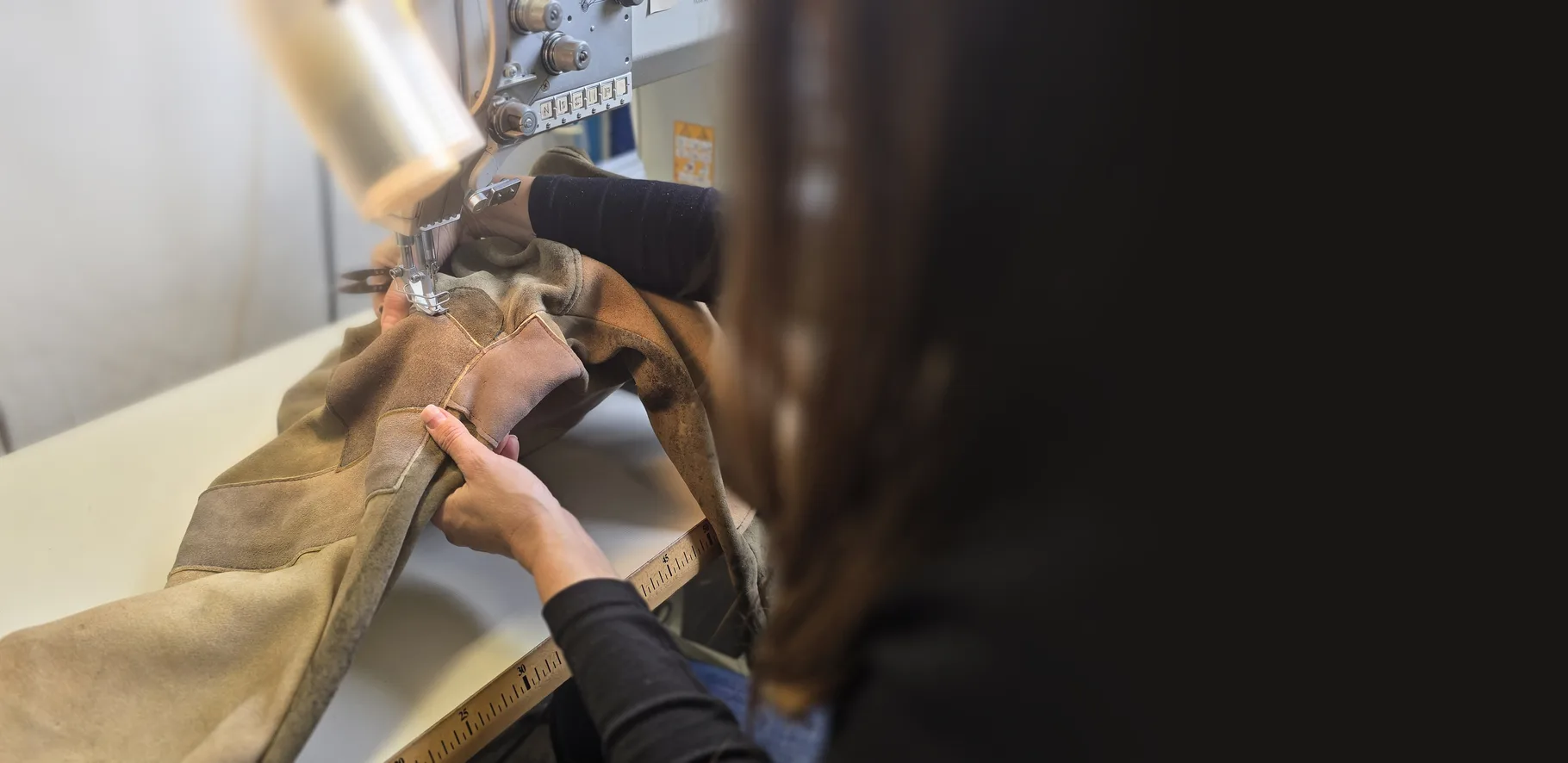 Schneiderin in unserer Werkstatt näht ein Kleidungsstück aus Leder