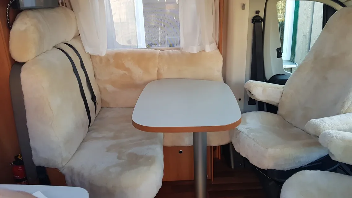 Maßgefertigte Lammfellbezüge in Farbe Sekt als Komplettausstattung im HYMER Exsis-t 588 auf Fiat Ducato – Sitzgruppe im Wohnraum und Pilotensitz