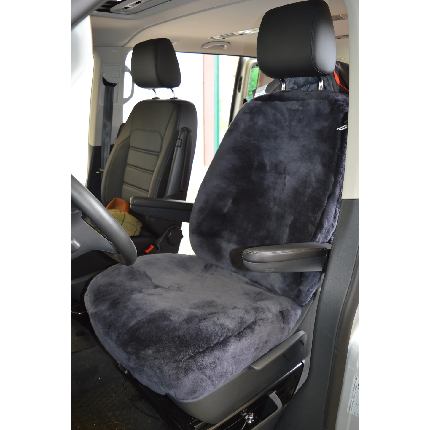 Maßgefertigter Autositzbezug aus Lammfell für VW T6/T6.1 in Farbe Anthrazit auf dem Fahrersitz mit Armlehnen, Vorderansicht