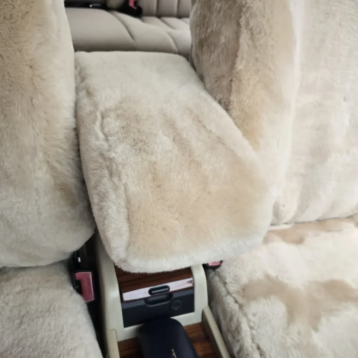 Detailansicht der mit Lammfell in Farbe Sand bezogenen Mittelarmlehne im Mercedes W124