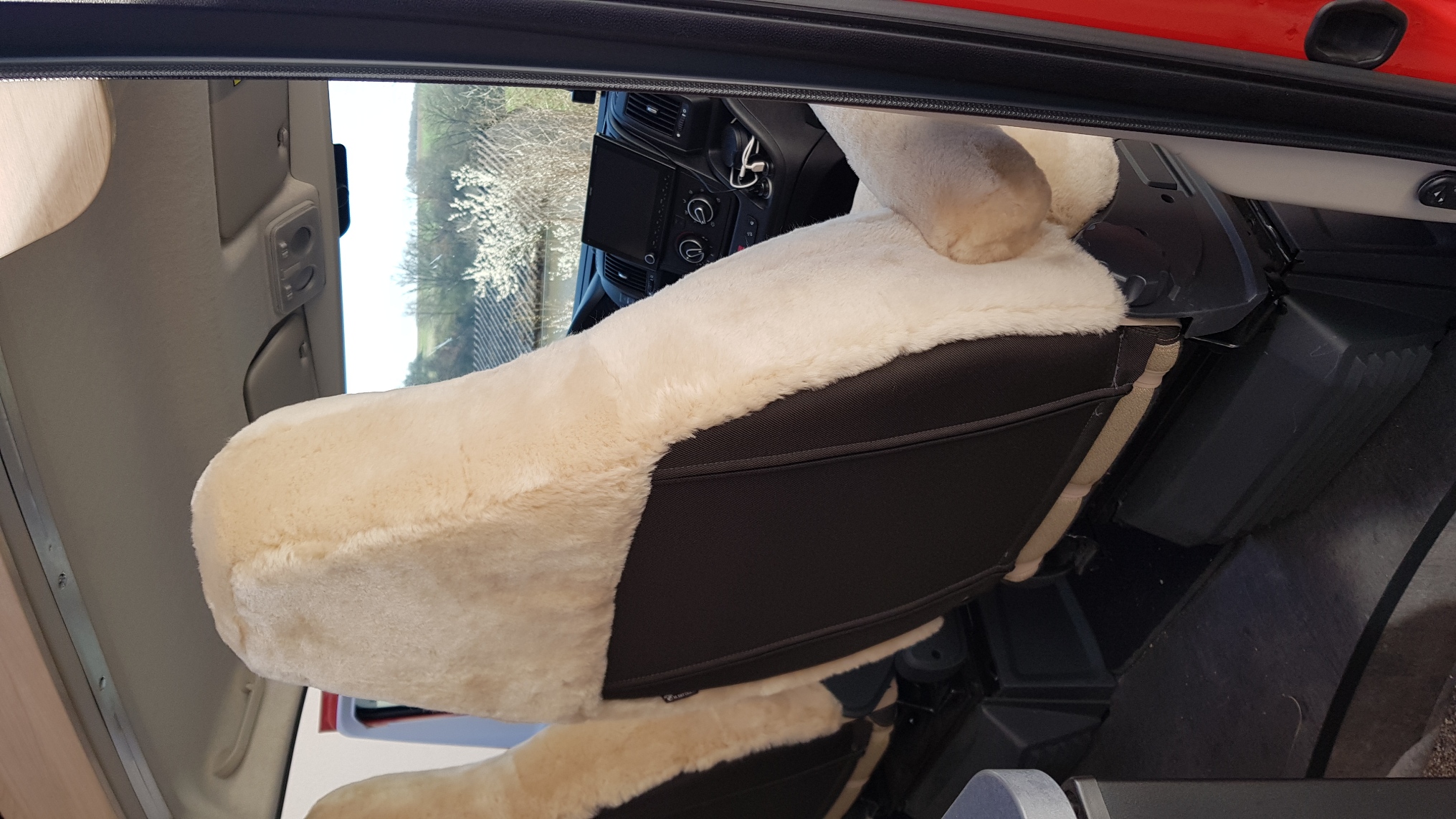 Fiat-Ducato-Einzelsitz mit Autositzbezug aus Lammfell in Farbe Sand und Armlehnen, von hinten gesehen