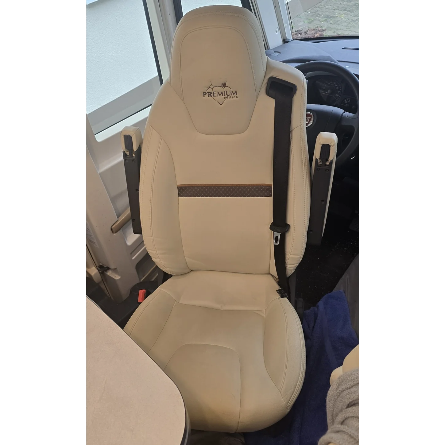 Originaler Fahrerhaussitz mit integriertem Sicherheitsgurt und Armlehnen im Wohnmobil auf Fiat-Ducato-Basis, ohne Lammfellbezug, in Vorderansicht