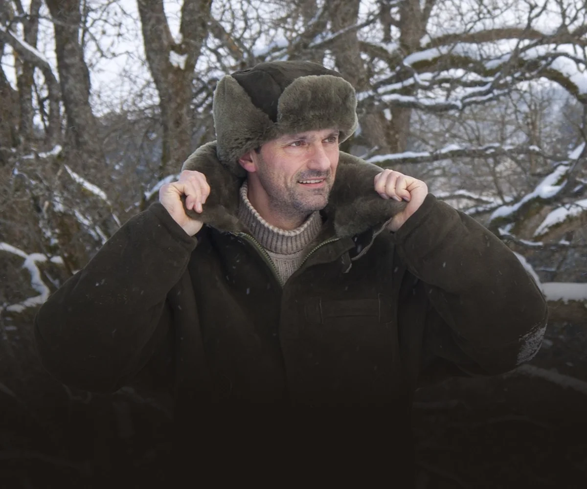 Jäger in Lammfelljacke im Winterwald